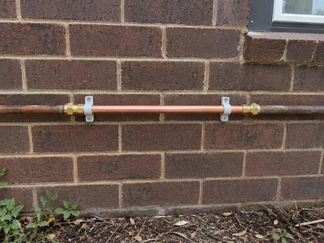 Horizontal copper pipe repair on a brick exterior wall with pipe clips in Maitland
